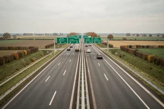 Vue aérienne d'un échangeur autoroutier français avec panneaux de signalisation verts et marquages au sol blancs