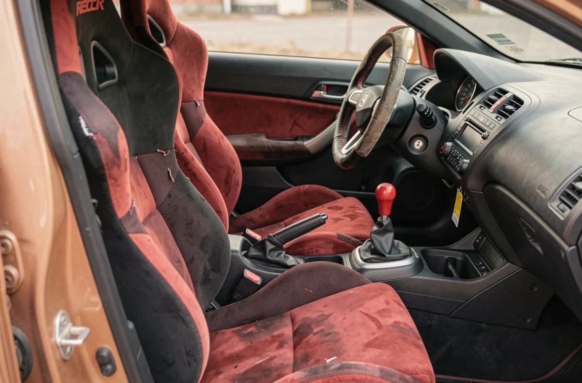 Intérieur de la Honda Civic Type R EP3 avec siège Recaro rouge usé, levier de vitesse et volant MOMO typiques